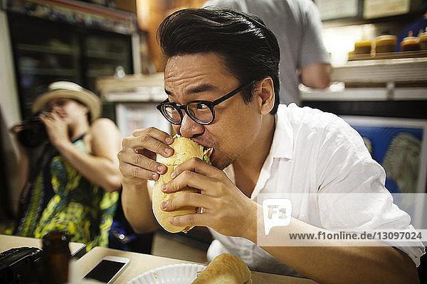 Close-up of man eating burger on table at restaurant