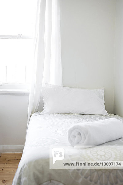 Kissen und zusammengerollte Decke im Bett am Fenster zu Hause
