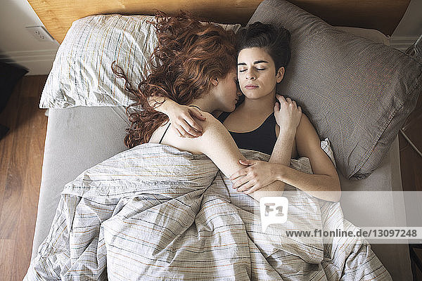 Hochwinkelansicht eines lesbischen Paares  das zu Hause auf dem Bett schläft