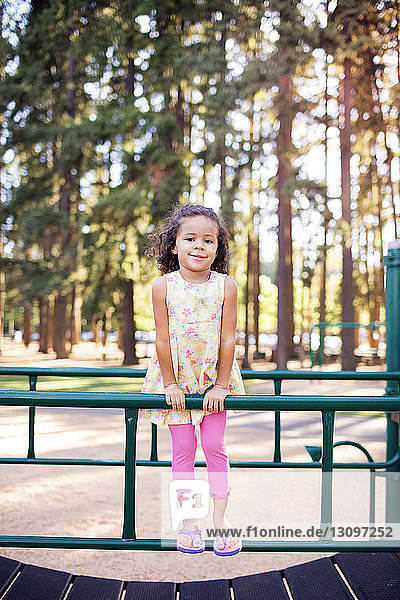 Portrait of girl standing on railing at playground