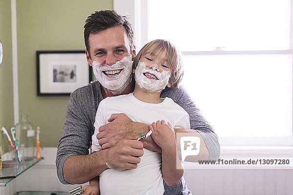Porträt von glücklichen Vater und Sohn mit Rasierschaum im Gesicht im Badezimmer stehend