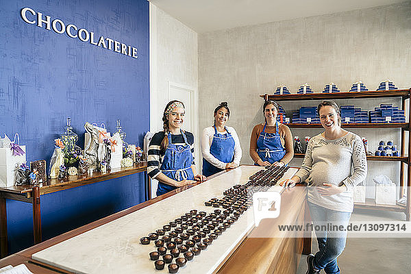 Porträt von lächelnden Mitarbeitern  die bei Tafelschokolade im Laden stehen