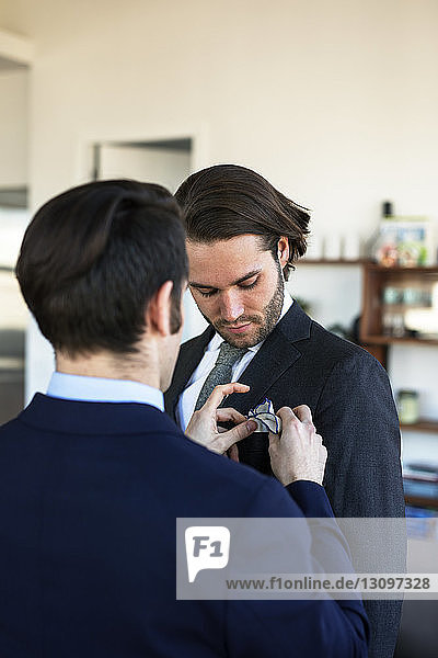 Rear view of man adjusting boyfriend's handkerchief while going to office