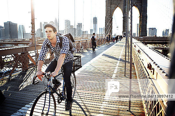 Mann fährt Fahrrad auf der Brooklyn Bridge gegen klaren Himmel