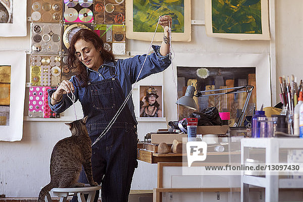 Happy female artist playing with cat in workshop