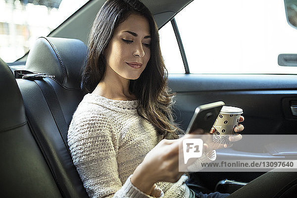 Junge Frau benutzt Smartphone im Taxi