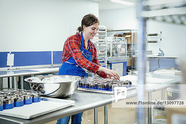 Lächelnde Köchin arrangiert Schokoladenbehälter in der Fabrik