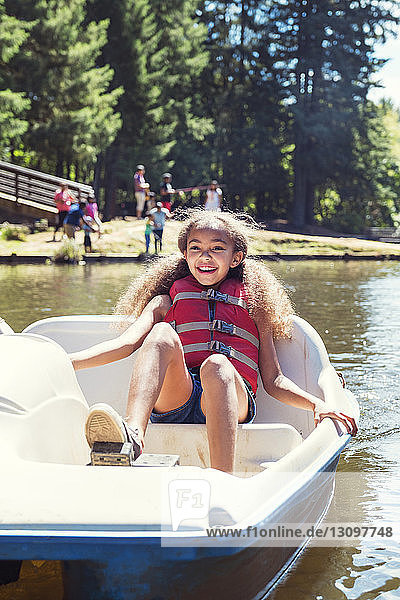 Smiling girl sitting in pedal boat on sunny day