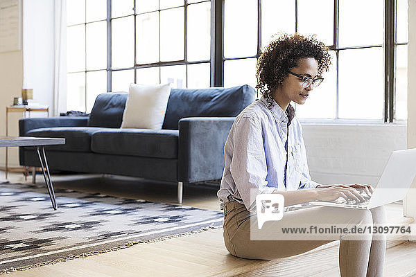 Businesswoman using laptop computer while sitting in lobby at office