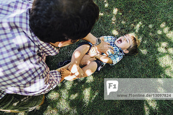 Hochwinkelaufnahme eines Vaters  der mit seinem Sohn auf einem Rasenfeld spielt