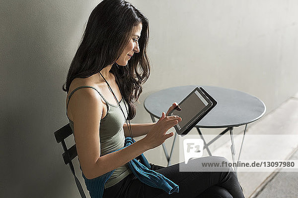 Junge Frau benutzt Tablet-Computer auf Stuhl im Freien