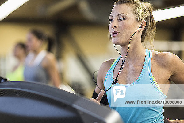 Frau schaut weg  während sie im Fitnessstudio auf dem Laufband trainiert
