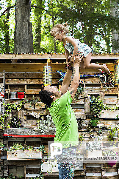 Verspielter Vater wirft Tochter in die Luft  während er im Hinterhof steht