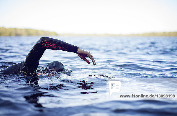 Ausgeschnittenes Bild einer Frau  die im See gegen den Himmel schwimmt