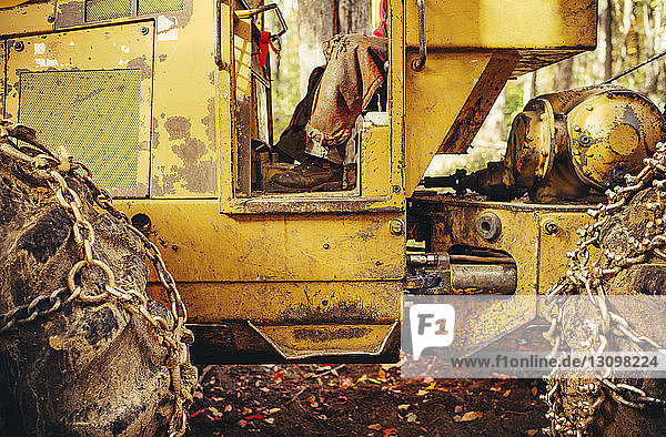 Niedriger Abschnitt eines Holzfällers  der in einem alten Baufahrzeug im Wald sitzt