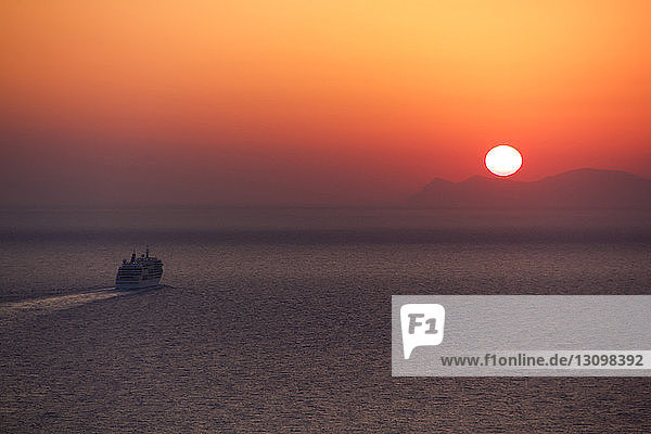 Hochwinkelansicht eines Bootes  das im Meer gegen den dramatischen Himmel bei Sonnenuntergang fährt
