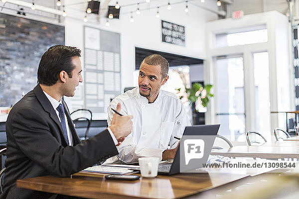 Businessman explaining with male chef in restaurant