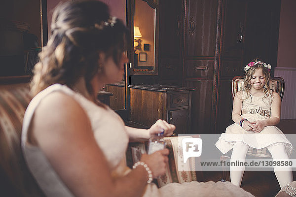 Braut und Blumenmädchen sitzen zu Hause auf Stühlen