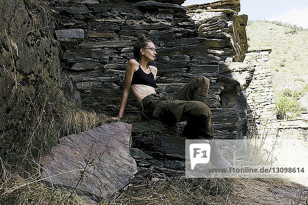 Nachdenkliche Wanderin schaut weg  während sie auf Felsen sitzt