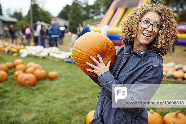 Woman holding pumpkin while standing at farm