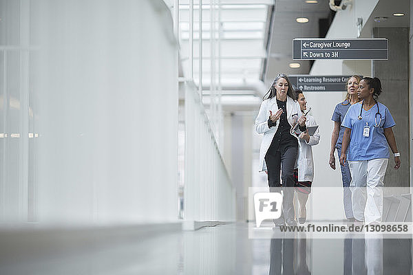 Female doctors discussing while walking in hospital corridor