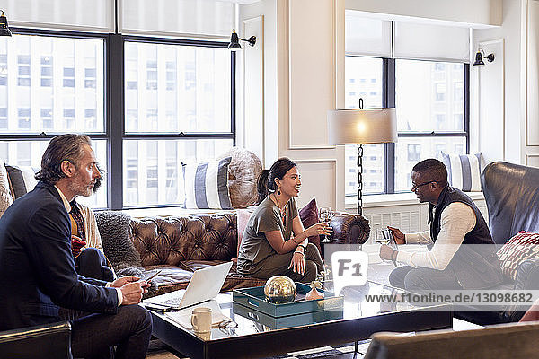 Businessman looking at colleagues talking while having wine in creative office