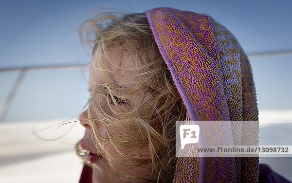 Side view of girl wearing scarf looking away while standing against sky during winter