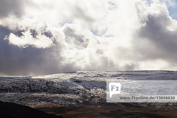 Landschaftliche Ansicht eines schneebedeckten Berges vor bewölktem Himmel