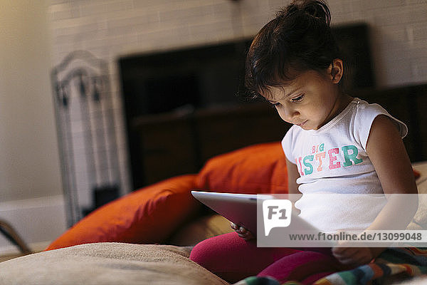 Mädchen benutzt Tablet-Computer zu Hause kniend