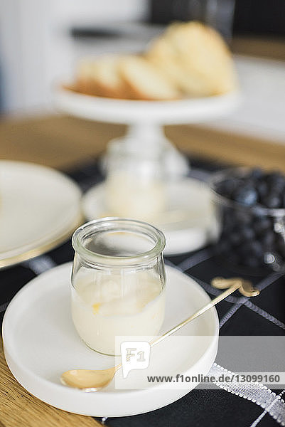 Hochwinkelansicht von Joghurt im Glas mit Löffel auf dem Tisch