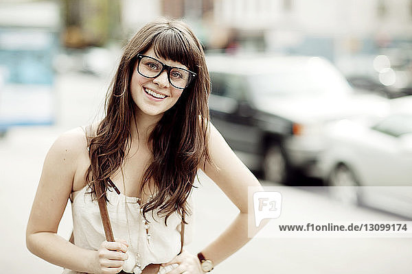 Porträt einer glücklichen Frau mit Geek-Brille  die auf dem Bürgersteig steht