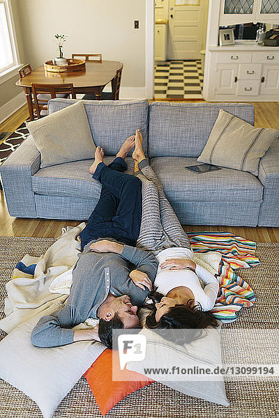 Hochwinkelansicht eines Paares  das sich zu Hause auf dem Teppich entspannt