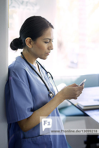 Ärztin benutzt Smartphone bei der Arbeit im Krankenhaus