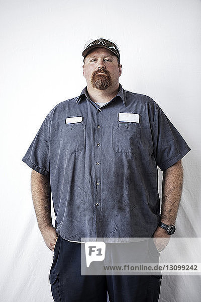 Portrait of confident worker standing against white background