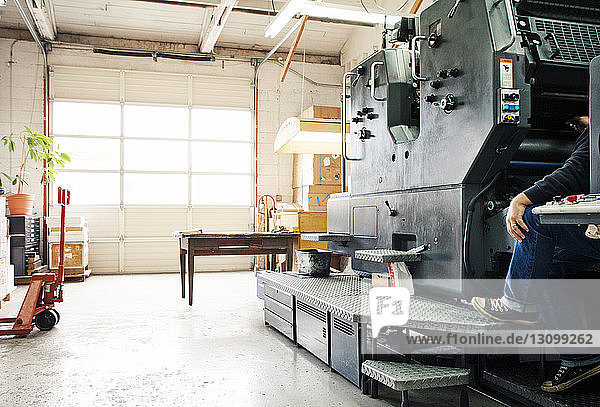 Männlicher Arbeiter bei der Bedienung einer Druckmaschine in der Werkstatt