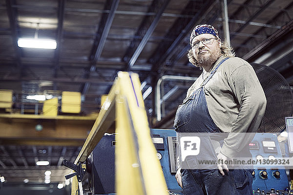 Low angle view of blue collar worker wearing bib overalls and headscarf while working in steel industry