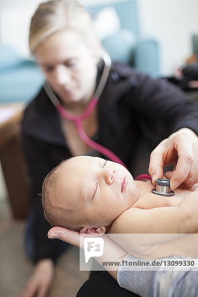 Arzt untersucht neugeborenes Baby Junge von Mutter gehalten