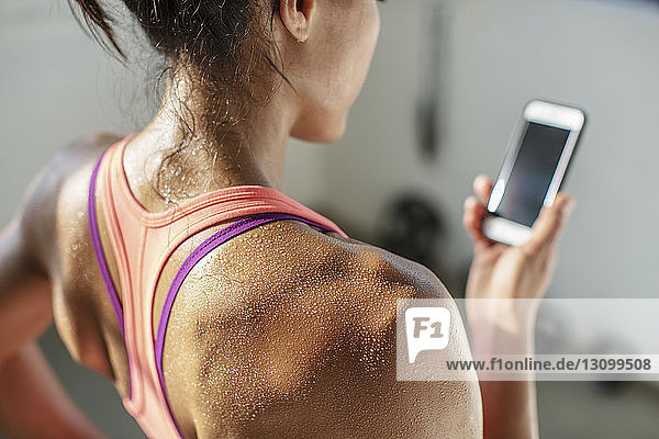 Nahaufnahme einer Sportlerin beim Gebrauch eines Mobiltelefons im Fitnessstudio