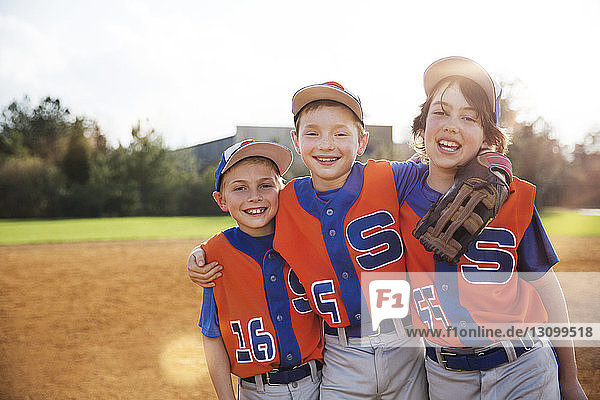 Portrait glücklicher Baseballspieler auf dem Spielfeld stehend