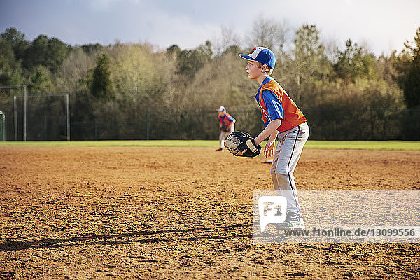 Seitenansicht eines Jungen  der auf dem Spielfeld Baseball spielt