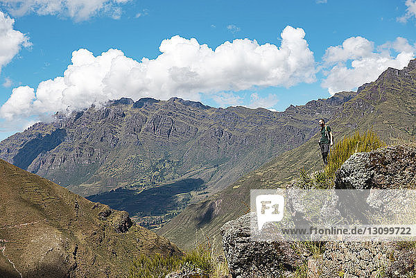 Side view of hiker looking at view while standing on mountain against sky at Pisac
