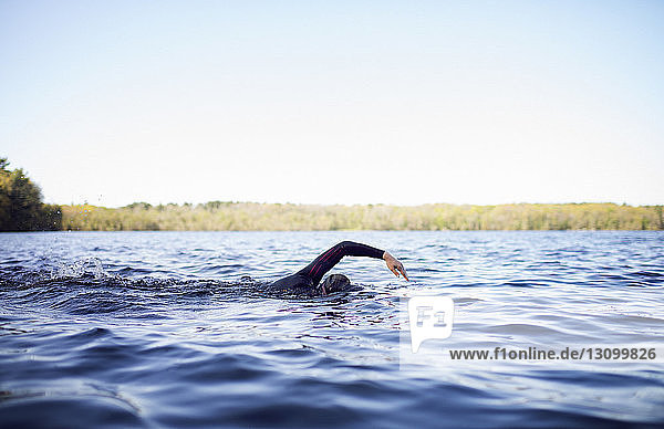 Frau schwimmt im See gegen klaren Himmel