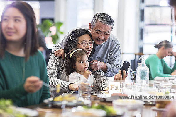 Grandparents taking selfie with granddaughter in restaurant