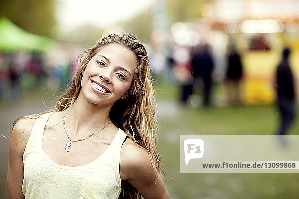 Portrait of happy young woman standing at amusement park