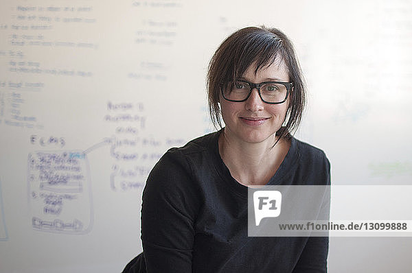 Porträt einer selbstbewussten Geschäftsfrau gegen Whiteboard im neuen Büro