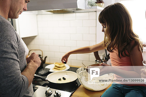 Vater und Tochter bereiten zu Hause in der Küche das Essen vor
