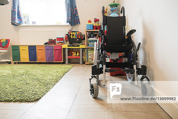 Leerer Rollstuhl und buntes Spielzeug zu Hause arrangiert