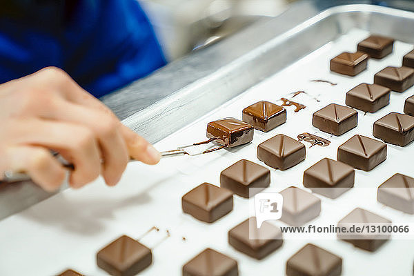 Geschnittene Hand des Küchenchefs beim Anrichten von Schokoladenstücken mit der Tauchgabel im Tablett