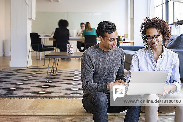 Geschäftsleute  die Laptop-Computer benutzen  während Kollegen im Büro arbeiten