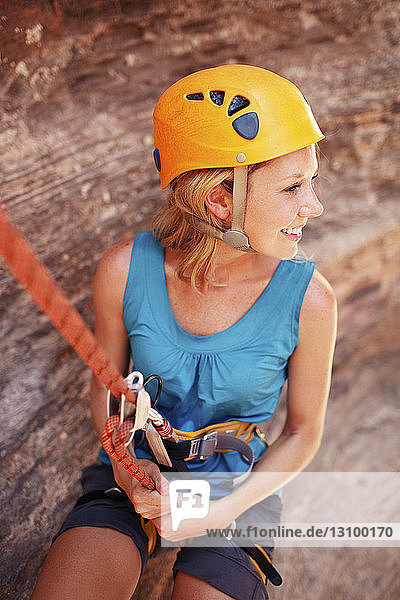 Lächelnde Frau hängt beim Wandern am Kletterseil